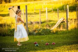 Flower girl playing croquet at a farm wedding